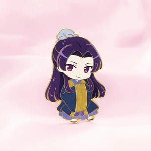 May include: A chibi-style enamel pin featuring a character with long purple hair and a blue and gold outfit. The character has large pink eyes and a serene expression. The pin has gold accents and a light blue headpiece.