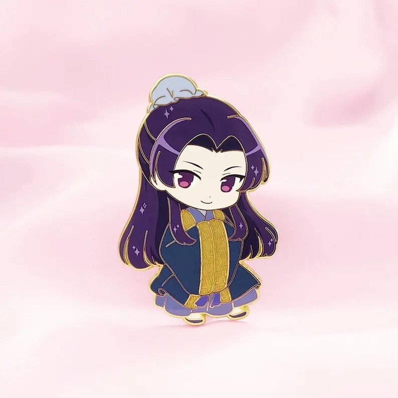 May include: A chibi-style enamel pin featuring a character with long purple hair and a blue and gold outfit. The character has large pink eyes and a serene expression. The pin has gold accents and a light blue headpiece.
