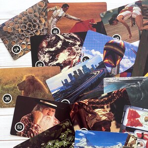 May include: A collection of vintage cards featuring various images. The cards depict a range of subjects, including a lion, a cityscape, a bullfighter, a hot air balloon, and a mountain scene. Each card has a number in a white circle.