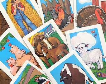 May include: A collection of rectangular playing cards featuring colorful cartoon illustrations of farm life, including a person with hay, a rooster, a turkey, pigs eating apples, a horse with a foal, a lamb, a goat, and a cow with a cat.