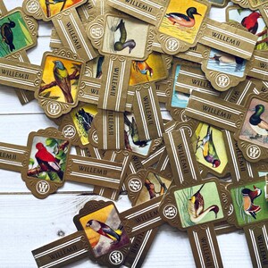 May include: A collection of vintage, gold-colored, paper labels with images of birds and the text "WILLEM II".
