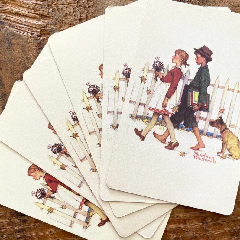 May include: A deck of playing cards featuring a Norman Rockwell illustration of two children walking past a white picket fence with a dog. The girl wears a red shirt and white dress, the boy a green jacket. The cards are fanned out.