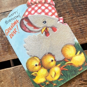 Puede incluir: Tarjeta de cumpleaños vintage con un diseño de gallina y pollitos. La tarjeta presenta una gallina con un gorro a cuadros rojos y blancos, con el texto "HAPPY BIRTHDAY GRANDMA DEAR!". Los pollitos son amarillos y el fondo es verde.