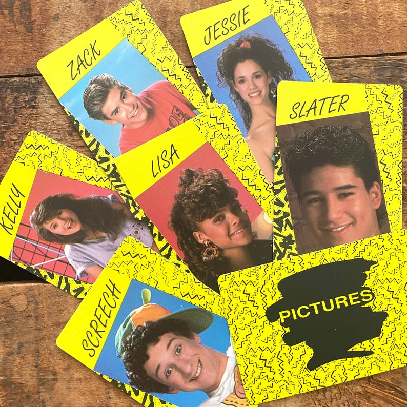 May include: A collection of vintage trading cards featuring images of characters from a television show. Each card has a yellow border with a black zig-zag pattern and a character's name. The cards are arranged on a wooden surface.