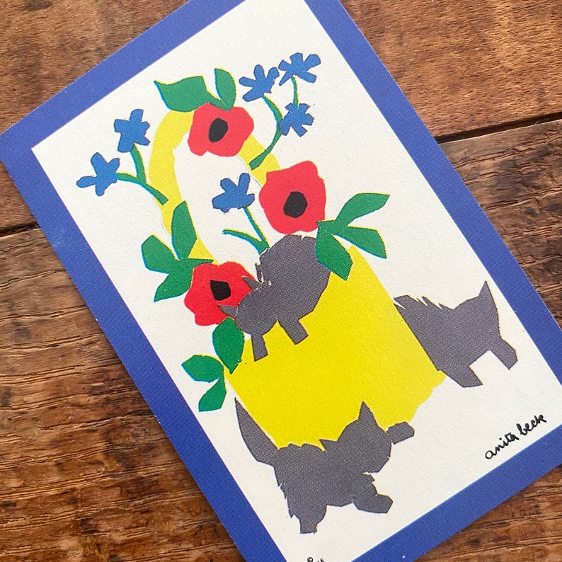 Puede incluir: Un jarr&oacute;n amarillo con borde azul lleno de flores rojas y blancas y tres siluetas negras de perros. El jarr&oacute;n est&aacute; sobre un fondo blanco con el texto "anita beck" en la esquina inferior derecha.