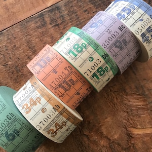 May include: A collection of vintage Chester City Transport bus ticket rolls in various colors, including green, orange, and purple. Each roll displays printed text and numbers, with a retro aesthetic. The rolls are arranged diagonally.