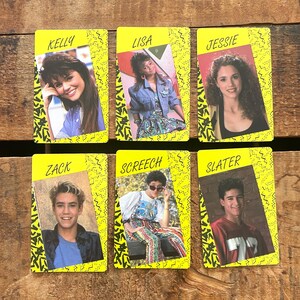 May include: Six vintage trading cards featuring cast members from a 1990s television show. Each card has a yellow background with a black zig-zag pattern and a photo of a character. The names "Kelly", "Lisa", "Jessie", "Zack", "Screech", and "Slater" are printed on the cards.