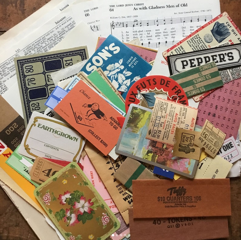 May include: A collection of vintage ephemera, including a sheet music page, a game board, a ticket stub, a vintage advertisement for Pepper's, and a small card with a floral design. The ephemera is arranged on a brown wooden surface.