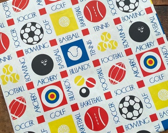 Puede incluir: Tela blanca con un patrón repetido de cuadrados rojos, amarillos, azules y negros. Cada cuadrado contiene un icono de deporte diferente, como un balón de fútbol, una pelota de béisbol, un balón de baloncesto, una pelota de golf, un pin de bolos, un balón de fútbol, una pelota de tenis, un blanco de tiro con arco y una bola de billar. Las palabras "Fútbol", "Golf", "Tiro con arco", "Bolos", "Fútbol", "Tenis", "Béisbol", "Baloncesto", "Billar" están impresas en la tela.