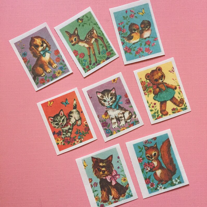 May include: Eight vintage illustrated cards featuring various animals and birds. The cards are rectangular and have a white background with colorful illustrations of a fawn, a cat, a squirrel, a dog, a teddy bear, and two birds. The cards are surrounded by a floral border.