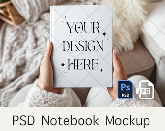 May include: A white notebook mockup with the text "YOUR DESIGN HERE." in black lettering. The notebook is being held by a person's hands. The image includes a PSD and JPG file icon.