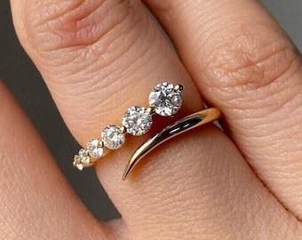 May include: A gold ring with a curved band and a row of small diamonds. The ring has a larger diamond set at an angle on the band.