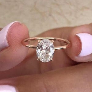 May include: A rose gold engagement ring with a large oval-shaped diamond.