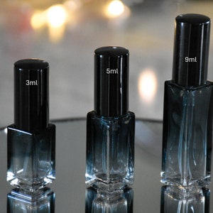 Op de afbeelding: Drie glazen flessen met zwarte doppen en een blauwe kleurverloop. De flessen zijn gelabeld met hun volume: 3 ml, 5 ml en 9 ml.