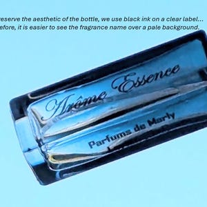 Op de afbeelding: Een blauwe glazen fles met een zwart etiket waarop "Tr&ocirc;me Essence Parfums de Marly" staat.