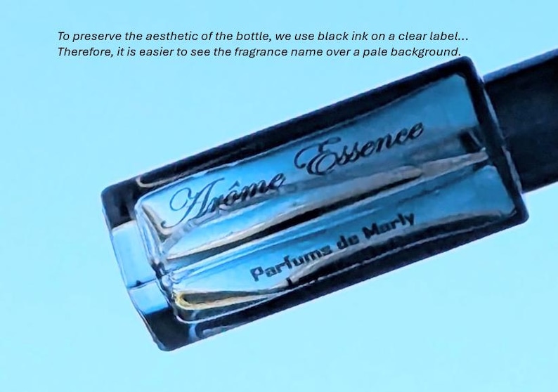 Op de afbeelding: Een blauwe glazen fles met een zwart etiket waarop "Tr&ocirc;me Essence Parfums de Marly" staat.