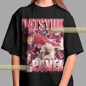 Könnte beinhalten: Schwarzes T-Shirt mit einem Grafikdruck im Vintage-Stil von Hockeyspielern Pavel Datsyuk und Datsyuk Pavel. Die Grafik zeigt die Spieler in ihren Trikots der Detroit Red Wings mit dem Text "Datsyuk Pavel" in fetter, roter Schrift.