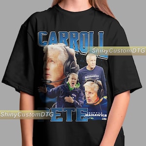 May include: Black t-shirt featuring a collage of images of Pete Carroll, with the name "CARROLL" in blue block letters at the top and "PETE" at the bottom. The shirt also includes the text "SEATTLE SEAHAWKS".