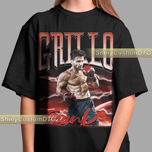 May include: Black t-shirt with a red and white graphic of a boxer with the text "Grillo Frank" on it.