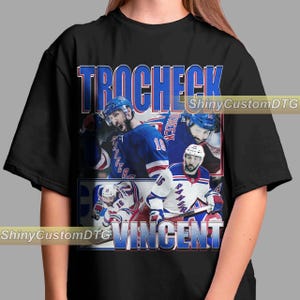 May include: Black t-shirt with a vintage-style graphic of hockey players. The graphic features the names "Trocheck" and "Vincent" and shows three hockey players wearing jerseys with the numbers 10, 16, and 18. The players are wearing blue, red, and white jerseys.