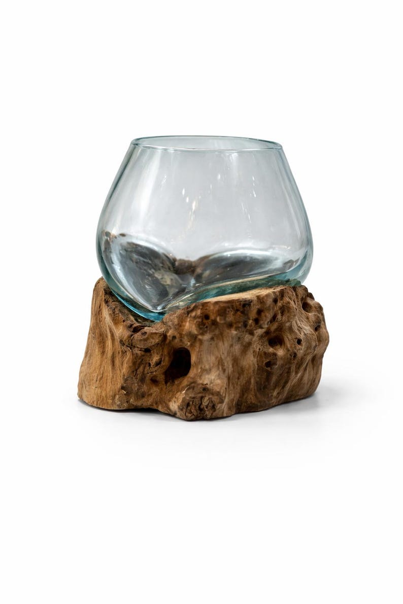 May include: A clear glass bowl with a rounded shape sits atop a natural, textured wooden base. The wood has a warm brown color with visible knots and holes, creating a rustic aesthetic. The bowl appears to be empty.
