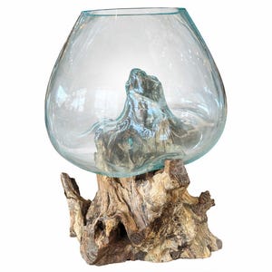 May include: A clear glass bowl with a rounded shape, resting on a natural wood base. The wood base has a rough, textured appearance with various shades of brown and gray. The bowl appears to be empty.