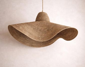Lampada a sospensione grande e ondulata in fibra naturale a forma di cappello, con paralume in erba marina.