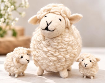 May include: A large cream-colored sheep figurine with a thick, textured wool-like body and two smaller matching sheep figurines positioned on either side. Each sheep features a smooth face, small dark eyes, and a stitched black nose and mouth.