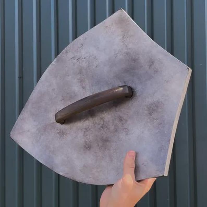 May include: A gray, curved trowel with a dark brown handle. The trowel has a rectangular shape with rounded edges and a textured surface. The handle is attached to the center of the trowel.