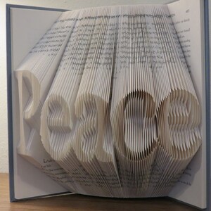 May include: A book with the word "Peace" folded into the pages. The book is open and the pages are folded to create the word in a 3D effect.