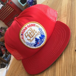 Puede incluir: Gorra de b&eacute;isbol roja y blanca con un parche bordado en oro y azul que dice "1969 All-Star Game 50th Anniversary" con un horizonte y la palabra "SOX".
