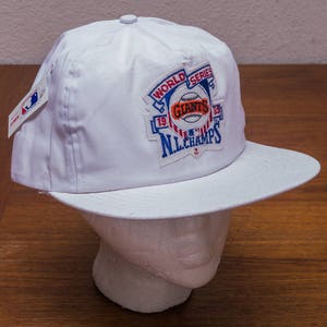 Pu&ograve; includere: Cappellino da baseball bianco con una toppa della World Series con il logo dei New York Giants e il testo "World Series" e "NL Champs".