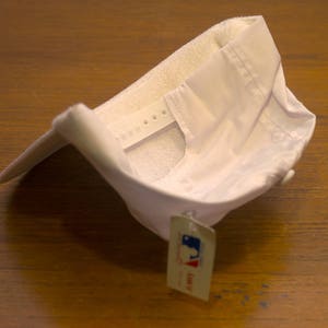 Pu&ograve; includere: Cappellino da baseball bianco con cinturino regolabile ed un'etichetta bianca con la scritta "Lids" su di essa.