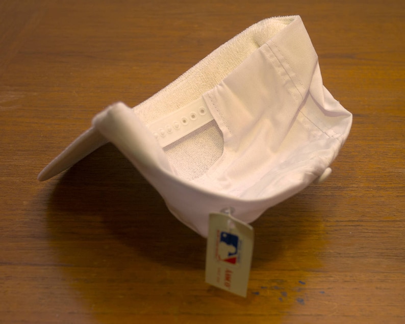 Pu&ograve; includere: Cappellino da baseball bianco con cinturino regolabile ed un'etichetta bianca con la scritta "Lids" su di essa.