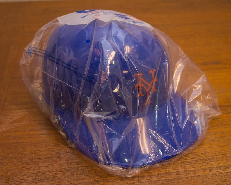 Puede incluir: Una gorra de b&eacute;isbol azul con el logotipo de los New York Yankees en naranja. La gorra est&aacute; empaquetada en una bolsa de pl&aacute;stico transparente.