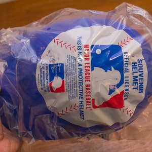 Puede incluir: Casco de b&eacute;isbol de pl&aacute;stico azul de recuerdo con el logotipo de la Major League Baseball y el texto "Souvenir Helmet Official License Major League Baseball This is not a protective helmet".