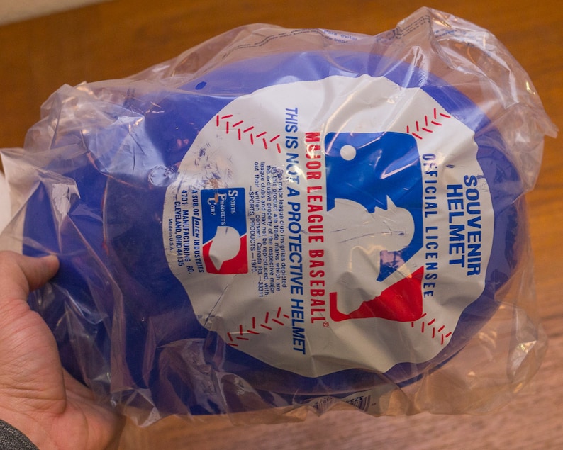 Puede incluir: Casco de b&eacute;isbol de pl&aacute;stico azul de recuerdo con el logotipo de la Major League Baseball y el texto "Souvenir Helmet Official License Major League Baseball This is not a protective helmet".