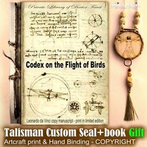 Peut inclure: Un manuscrit relié intitulé Codex on the Flight of Birds avec des croquis de Léonard de Vinci et un pendentif circulaire représentant l'Homme de Vitruve. Le pendentif est suspendu par un cordon avec des perles en bois et un pompon.