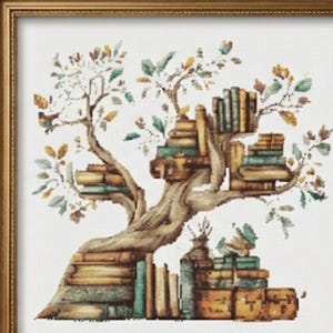 May include: A framed cross-stitch artwork depicts a tree composed of stacked books, with leaves and branches. The artwork is in a gold frame, set against a window with a view of a building. Wooden spools of thread and embroidery floss are on the table.