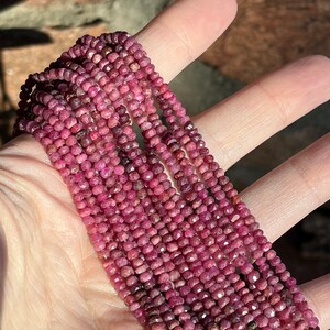 May include: A strand of pink ruby beads, faceted and round, strung together on a thread. The beads are small and uniform in size, creating a delicate and elegant look.