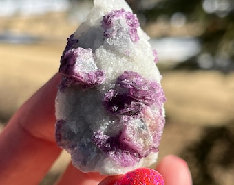 May include: A cluster of purple fluorite crystals on a white quartz matrix. The crystals are translucent and have a glassy luster. The fluorite crystals are clustered together in a random pattern.