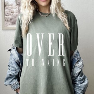 May include: A green oversized t-shirt with the text "OVER THINKING" printed in white.