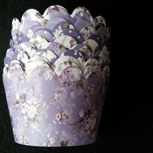 May include: A stack of purple and white cupcake liners with a floral pattern. The liners have a scalloped edge.