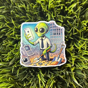 May include: A green alien wearing a tie and holding a smartphone with a bitten apple logo. The alien is standing in a destroyed city with a shovel and a pickaxe. The background is a cityscape with a building in the background.