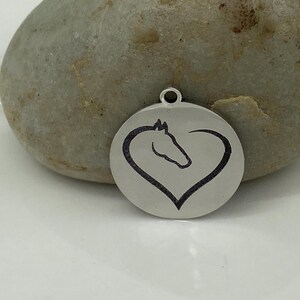 May include: A silver pendant with a horse head silhouette inside a heart shape.