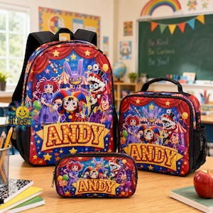 Puede incluir: Un conjunto de mochila, bolsa de almuerzo y estuche con un gráfico colorido de temática circense, personajes y el nombre ANDY en una fuente estilo marquesina. Los artículos son principalmente rojos y azules con detalles de estrellas amarillas.