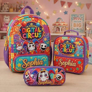 Op de afbeelding: Een set bestaande uit een rugzak, lunchtas en etui met The Amazing Digital Circus-branding, kleurrijke karakterafbeeldingen, sterren en de naam Sophia in een geel cursief lettertype op elk item tegen een levendige achtergrond met patronen.