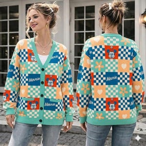 May include: A long-sleeve button-down cardigan featuring a multi-colored checkerboard pattern in shades of teal, orange, and white. The knit garment displays repeating graphics of Minnie Mouse, white flowers, and hearts, with the text Minnie printed.
