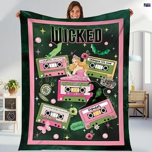 Könnte beinhalten: Eine dunkelgrüne Decke mit einem rosa Rand, die das Wort "WICKED" und Illustrationen von Kassetten, einer Prinzessin, einer Hexe und anderen thematischen Grafiken zeigt. Die Decke hat ein skurriles Design mit verschiedenen Farben und Formen.