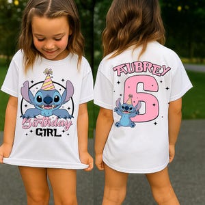 May include: White t-shirt featuring a cartoon character with a party hat. The front of the shirt says "Birthday Girl" with the character. The back of the shirt has the name "Aubrey" and the number "6" in pink.